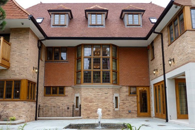 Ispirazione per la facciata di una casa beige american style a tre piani con rivestimento in mattoni e tetto a capanna