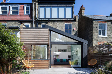 Medium sized and multi-coloured contemporary rear house exterior in London with three floors, mixed cladding, a lean-to roof and a metal roof.