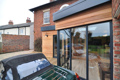 Photo of a medium sized and multi-coloured contemporary two floor house exterior in Other with wood cladding and a flat roof.