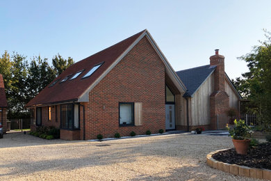 Esempio della facciata di una casa contemporanea a due piani di medie dimensioni con rivestimento in mattoni, tetto a capanna e copertura in tegole