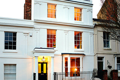 Foto della facciata di una casa grande bianca a tre piani con rivestimento in mattoni e tetto piano