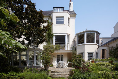 Large and white classic render house exterior in London with three floors, a mansard roof and a tiled roof.