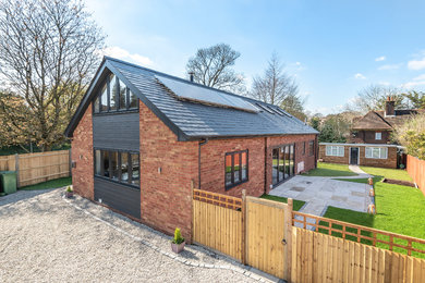 This is an example of a medium sized and gey contemporary two floor detached house in Dorset with concrete fibreboard cladding, a pitched roof and a tiled roof.