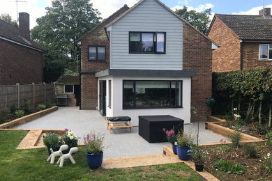 Medium sized and gey contemporary two floor detached house in Hertfordshire with concrete fibreboard cladding, a pitched roof and a tiled roof.