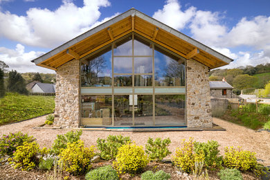 Diseño de fachada de casa actual grande de dos plantas con revestimiento de piedra, tejado a dos aguas y tejado de teja de barro