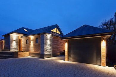 Cette photo montre une grande façade de maison moderne avec un toit à deux pans et un toit en tuile.