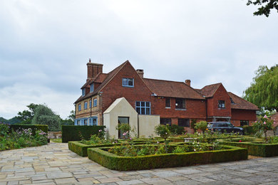 Imagen de fachada de casa clásica grande de dos plantas con revestimiento de piedra, tejado a dos aguas y tejado de teja de barro