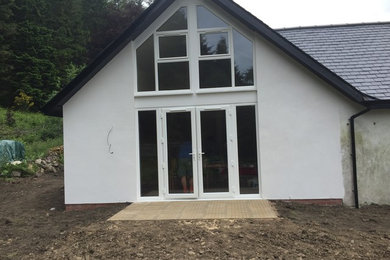This is an example of a medium sized and white rural two floor render house exterior in Other with a pitched roof.