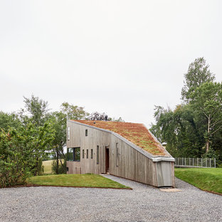 Cette image montre une façade de maison marron chalet à deux étages et plus avec un toit végétal et un toit plat.