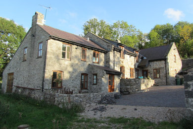 Diseño de fachada gris de estilo de casa de campo grande a niveles con revestimiento de piedra y tejado a dos aguas