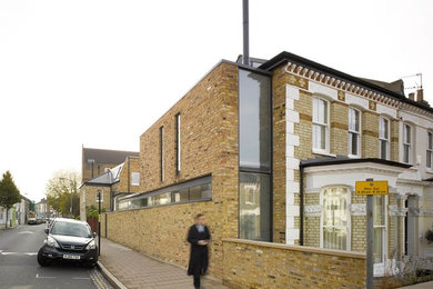Large and brown contemporary brick semi-detached house in London with three floors, a pitched roof and a tiled roof.
