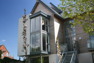 Foto de fachada de casa blanca actual de tamaño medio de tres plantas con revestimiento de madera, tejado a dos aguas y tejado de teja de barro
