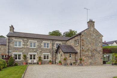 Imagen de fachada de casa bifamiliar beige campestre grande de dos plantas con revestimiento de piedra, tejado a dos aguas y tejado de teja de barro