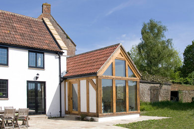 Ejemplo de fachada de casa blanca tradicional de tamaño medio de dos plantas con revestimiento de estuco, tejado a dos aguas y tejado de teja de barro