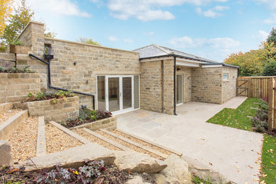 Immagine della facciata di una casa contemporanea a un piano di medie dimensioni con rivestimento in pietra e tetto a padiglione
