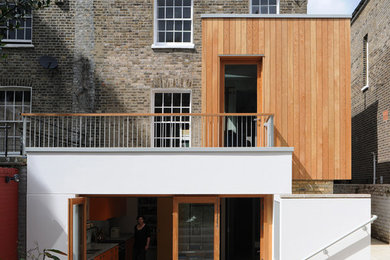 Photo of a medium sized contemporary terraced house in London with wood cladding, three floors and a hip roof.