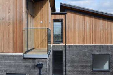 Photo of a large and gey contemporary two floor detached house in Other with wood cladding, a pitched roof and a metal roof.