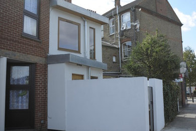 На фото: маленький, белый, двухэтажный дом в современном стиле с облицовкой из цементной штукатурки для на участке и в саду с
