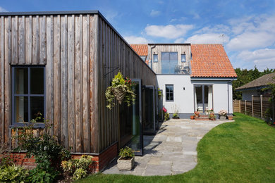 Cette photo montre une façade de maison blanche tendance en bois de taille moyenne et à un étage avec un toit plat et un toit végétal.