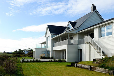 Diseño de fachada de casa beige costera grande de dos plantas con tejado a cuatro aguas y tejado de varios materiales