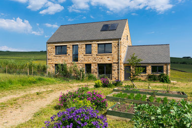 Photo of a rural two floor house exterior in Other with stone cladding and a pitched roof.