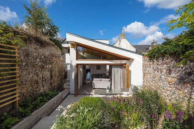 Inspiration för små moderna vita hus, med allt i ett plan, platt tak och stuckatur