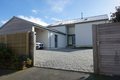 Réalisation d'une façade de maison design en bois à un étage avec un toit à deux pans et un toit en métal.
