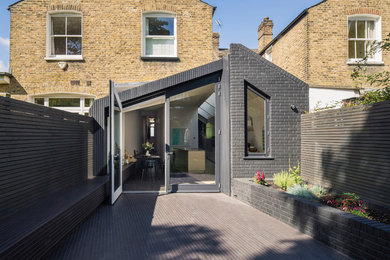 Black contemporary bungalow brick terraced house in London with a pitched roof and a mixed material roof.
