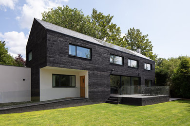 Réalisation d'une façade de maison noire minimaliste avec un toit à deux pans.