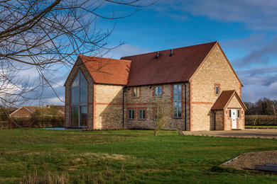 Large and multi-coloured classic two floor detached house in Oxfordshire with stone cladding, a pitched roof and a tiled roof.