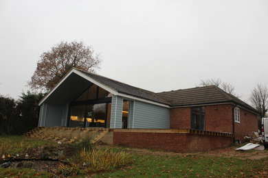 This is an example of a large and blue contemporary bungalow house exterior in Kent with concrete fibreboard cladding and a hip roof.