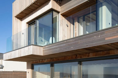 Photo of a large contemporary detached house in Sussex with wood cladding.