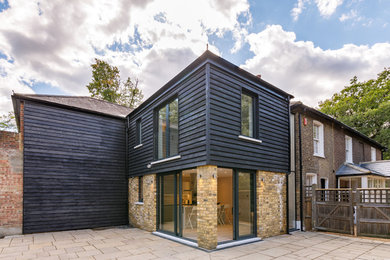 Пример оригинального дизайна: двухэтажный, деревянный, черный дуплекс среднего размера в современном стиле с вальмовой крышей и черепичной крышей