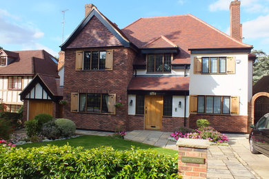 Design ideas for a large and red traditional brick house exterior in London with three floors and a pitched roof.
