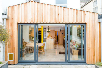 Photo of a medium sized and white contemporary bungalow terraced house in Devon with wood cladding, a pitched roof and a metal roof.