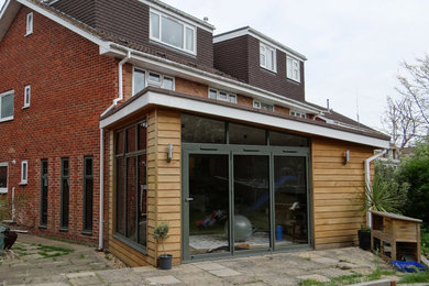 This is an example of a contemporary bungalow house exterior in Hampshire with wood cladding.