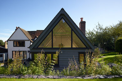 Photo of a gey and medium sized traditional bungalow house exterior in Hertfordshire with wood cladding and a pitched roof.