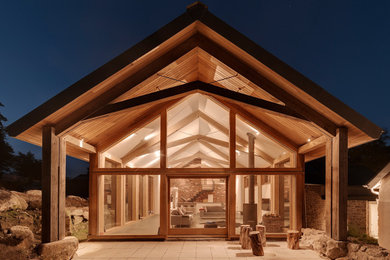 Immagine della facciata di una casa grande marrone contemporanea a due piani con rivestimento in legno e tetto a capanna