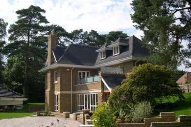 Photo of a large and beige traditional brick house exterior in Hampshire with three floors.