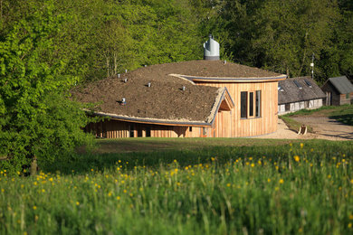 This is an example of a small contemporary bungalow house exterior in Gloucestershire with wood cladding, a pitched roof and a green roof.