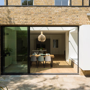 Foto de fachada de casa amarilla, contemporánea, de tres plantas, con revestimiento de ladrillo y tejado de varios materiales