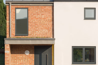 Mittelgroße, Zweistöckige Moderne Doppelhaushälfte mit Mix-Fassade, weißer Fassadenfarbe, Satteldach, Blechdach und grauem Dach in Cambridgeshire