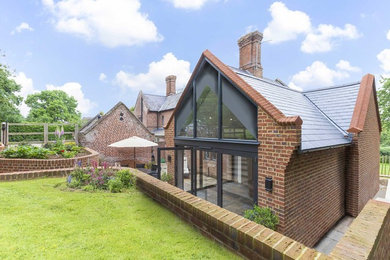 This is an example of a medium sized and red traditional two floor brick house exterior in Kent.