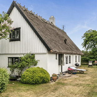 Lantlig inredning av ett mellanstort vitt hus, med två våningar och sadeltak