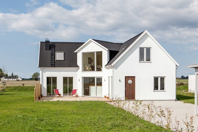 Imagen de fachada de casa blanca nórdica de dos plantas con revestimiento de piedra y tejado a dos aguas