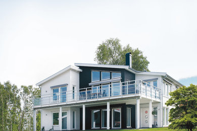 Diseño de fachada blanca escandinava extra grande de dos plantas con revestimiento de madera y tejado de un solo tendido