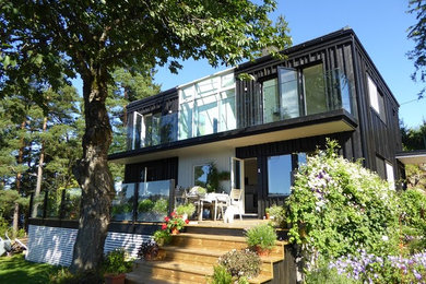 Diseño de fachada negra minimalista de tamaño medio de dos plantas con revestimiento de madera
