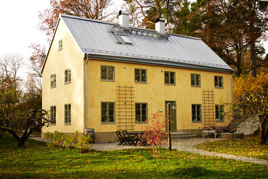 Idee per la facciata di una casa gialla classica a tre piani di medie dimensioni con rivestimento in pietra e tetto a capanna