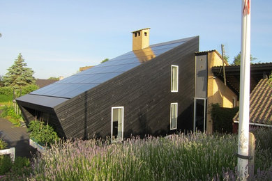 Modelo de fachada negra contemporánea de tamaño medio de dos plantas con revestimiento de madera y tejado a la holandesa