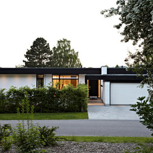 Inspiration för ett stort funkis vitt hus i flera nivåer, med platt tak